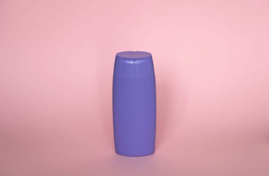 Violet blank unbranded cosmetic plastic bottle for shampoo, gel, lotion, cream, bath foam pink background