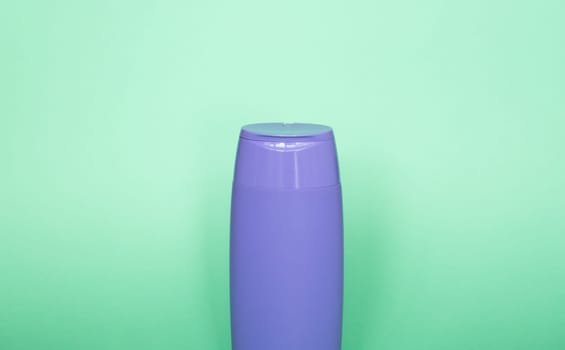 Violet blank unbranded cosmetic plastic bottle for shampoo, gel, lotion, cream, bath foam green background