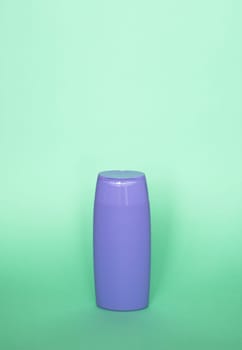 Violet blank shampoo bottle or shower gel on pastel green background. Container, beauty product and body care cosmetics