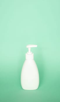 White plastic soap dispenser pump bottle on pastel green background. Skin care lotion, shampoo bottle, bath and body lotion. Bathroom Accessories