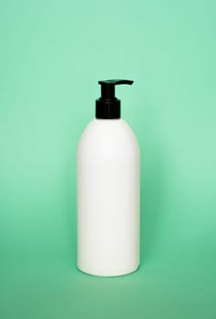 White plastic soap with black dispenser pump bottle on pastel green background. Skin care lotion, shampoo bottle, bath and body lotion. Bathroom accessories