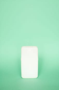 White square shampoo bottle or shower gel on pastel green background. Container, beauty product and body care cosmetics