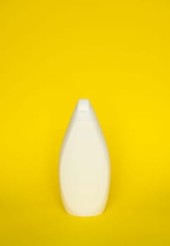 White shampoo bottle or shower gel on yellow background. Container, beauty product and body care cosmetics