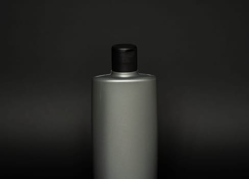 Grey liquid container for gel, lotion, cream, shampoo, bath foam. Cosmetic plastic bottle on black background. Cosmetic packaging mockup with copy space