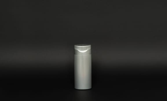 Blank grey bottle for shampoo or shower gel on black background