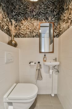 a bathroom with a toilet, sink and mirror on the wall next to it is a palm leaf pattern covering the walls