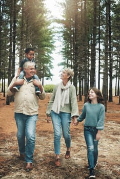 Family, grandparents and children in forest adventure together for quality bonding time in nature. Happy grandpa, grandma and kids enjoying a fun walk, hike or stroll in the woods in the outdoors.