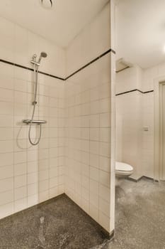 a bathroom with white tiles on the walls and black trim around the shower head, which is attached to the wall