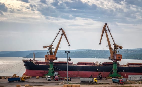 Two giant Port cranes load grain from cargo ships. horizontal view