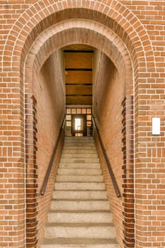 a brick building with stairs leading up to the front door and an open doorway on the right hand side,