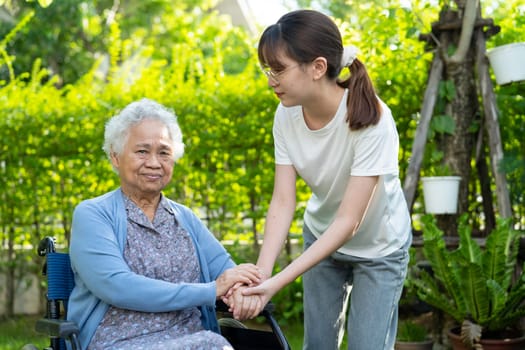 Caregiver help and care Asian elderly woman use walker with strong health while walking at park in happy fresh holiday.