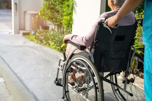 Caregiver help and care Asian elderly woman patient sitting on wheelchair to ramp in nursing hospital, healthy strong medical concept.