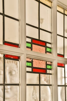 a window with many different colored glass pieces on it and the reflection in the window is white, red, green and black