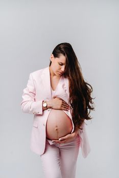 pregnant woman in pink suit close-up on gray background.