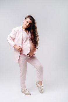 pregnant woman in pink suit close-up on gray background.