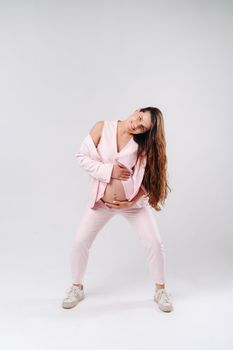 pregnant woman in pink suit close-up on gray background.