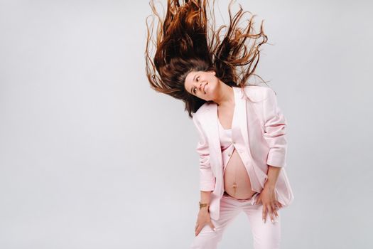 pregnant woman in pink suit close-up on gray background.