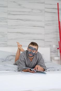 Womens health. Spa and wellness. Woman with face mask relaxing lying on the bed reading a magazine