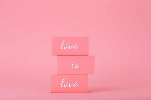 Love is love elegant concept in bright pink colors. Love is love written on pink rectangular blocks against pink background. Concept of Lgbtq pride social post, tolerance, respect and equal rights