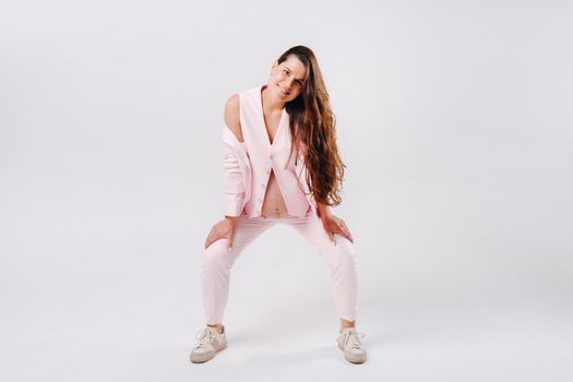 pregnant woman in pink suit close-up on gray background.