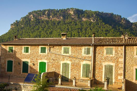 Classical spanish villa, mediterranean house exterior, traditional architecture with stone wall. Typical mediterranean region residential building with wooden shutters.