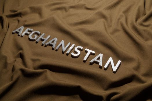 the word afghanistan laid with silver metal letters on tan khaki canvas fabric