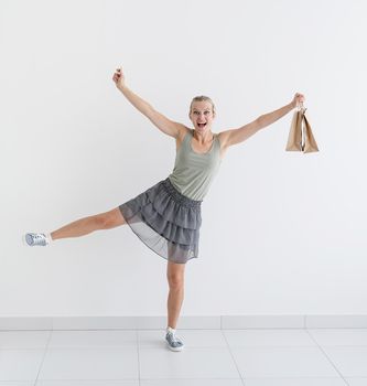 Online shopping concept. smiling woman dancing with eco friendly shopping bags and creadit card