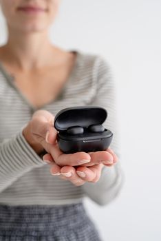 Wireless technology. Young woman holding wireless earbuds