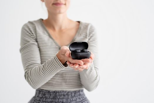 Wireless technology. Young woman holding wireless earbuds