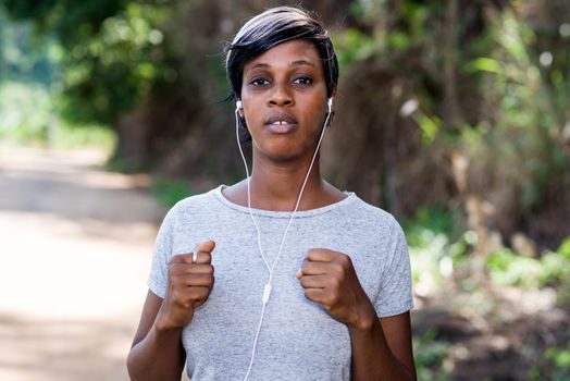Young woman running in sportswear while listening to music in the middle of nature