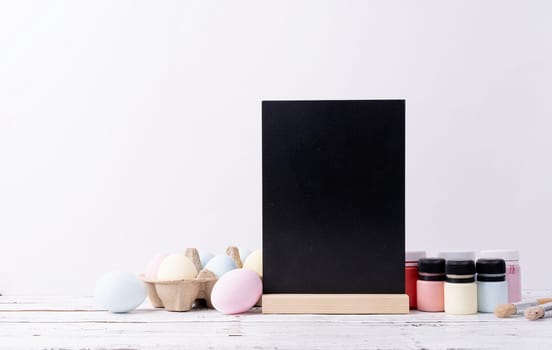 Spring holidays, Happpy Easter. Pastel colored Easter eggs and mimosa flowers with blank white frame for mockup design, front view on white brick wall background