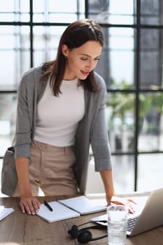 Young business woman standing in her home office writing notes.