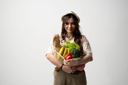 Zero waste concept with copy space. Woman holding a reusable mesh shopping bag with vegetables, products. Eco friendly mesh shopper. Zero waste, plastic free concept