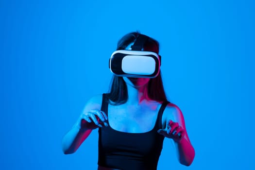 Brunette woman in a black top wearing virtual reality goggles in modern coworking studio