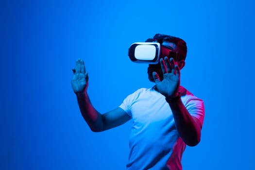 Bearded brunette man in white t-shirt wearing virtual reality goggle and immersing himself in VR multimedia. Future technology concept