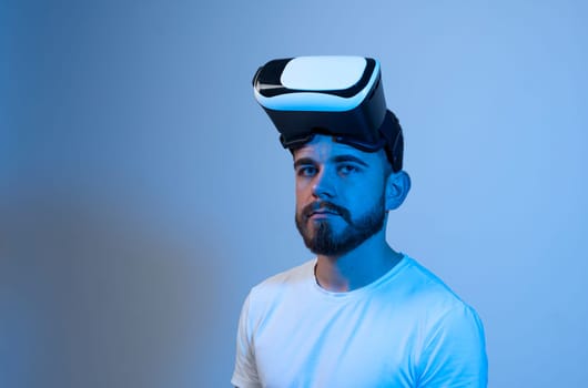 Portrait of young attractive bearded man with a virtual reality goggles forehead. VR headset. Virtual reality concept