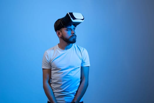 Portrait of young attractive bearded man with a virtual reality goggles forehead looks away. VR headset. Virtual reality concept