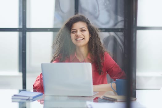 Portrait of Young Successful Caucasian Businesswoman Sitting at Desk Working on Laptop Computer in City Office