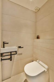 a white toilet in a small bathroom with beige tiles on the walls, and a wall mounted mirror above it