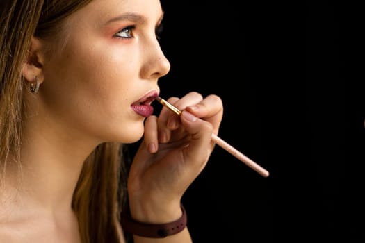 Make-up artist apply red lipstick. Part of attractive woman's face with fashion red lips makeup