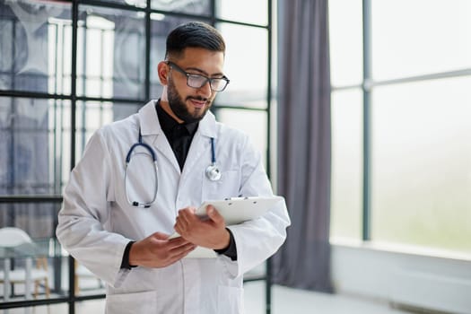 Smiling male doctor with arms crossed in hospital