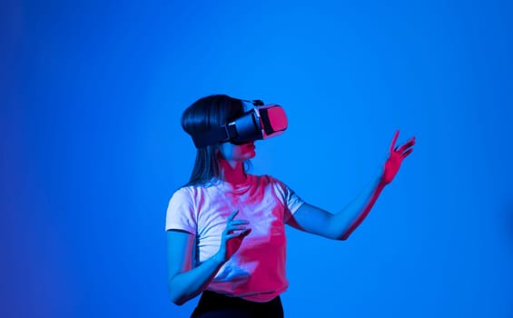 Brunette woman in virtual reality headset playing a video games with a friend's and gesturing with a hands. Future gaming concept