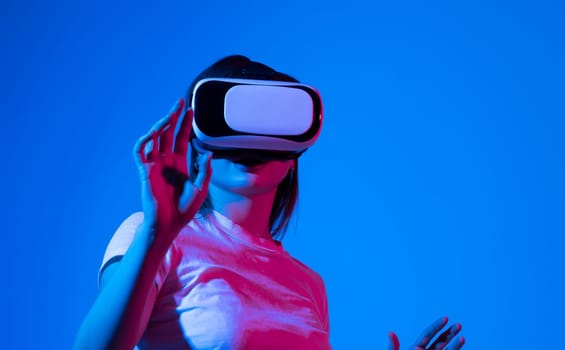 Woman in white shirt wearing VR glassess, VR set equipment for exploring a metaverse. Girl wearing a VR headset and interacting with virtual reality. Simulation, AR and metaverse concept