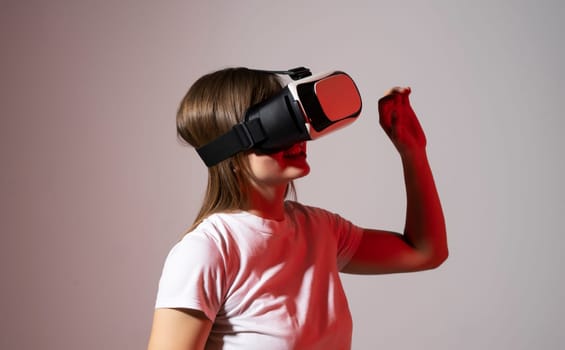 Woman gamer in white t-shirt wearing virtual reality headset and playing a video games with a friend's and gesturing with a hands in a red light. Future gaming concept