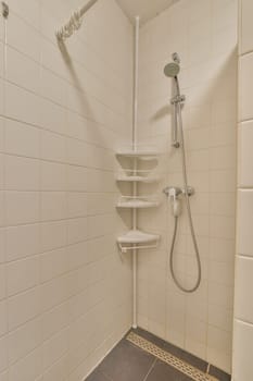 a shower room with tiled floor and white tiles on the walls, there is a shelf above the shower head