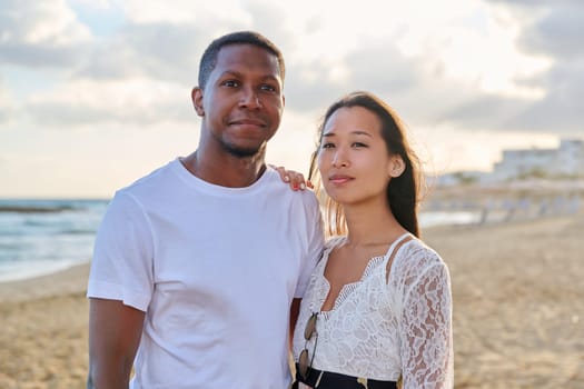 Young couple in love on the beach together. Multiethnic couple, asian woman and african american man. Love, honeymoon, relationship, lifestyle, togetherness, happiness, dating, multicultural family concept