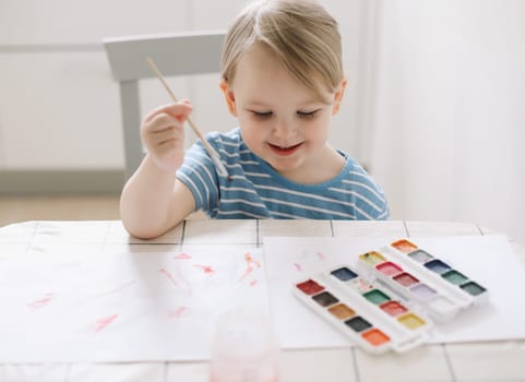 Small preschooler girl sit at desk painting, quarantine, homeschooling concept