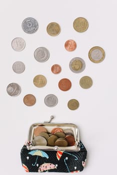 Open purse with different coins isolated on white background top view. Financial crisis, poverty, lack of money