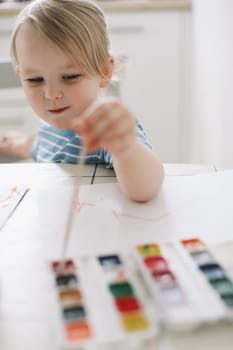 Small preschooler girl sit at desk painting, quarantine, homeschooling concept