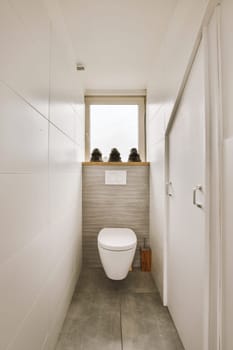 a toilet in the corner of a bathroom with two people sitting on the window ledge above it and looking out